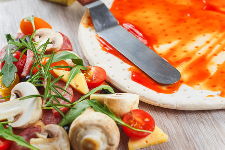 Pizza cooking. Applying tomato sauce on the doughの写真素材
