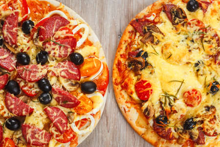 Two big hot and tasty pizzas with olives, mushrooms and salamiの写真素材