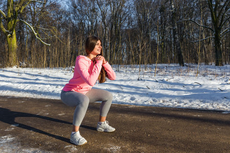 A young girl goes in for sports in winter park. Squats are one of the General developmental...