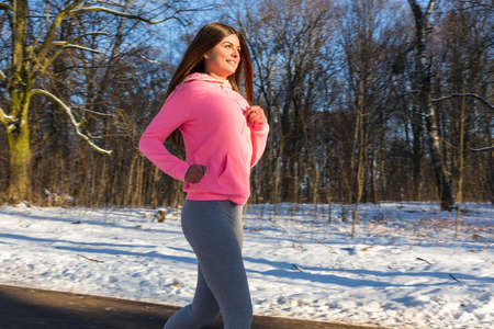 Young girl goes in for sports in winter park. Jogging training.の写真素材