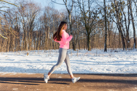 Young girl goes in for sports in winter park. Jogging training.