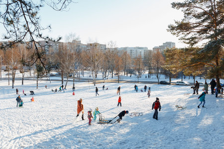 GRODNO, BELARUS - DEC 04: Families enjoy sledding on a snowy hill in a city Park at December 04, 2016 in Grodno, Belarusのeditorial素材