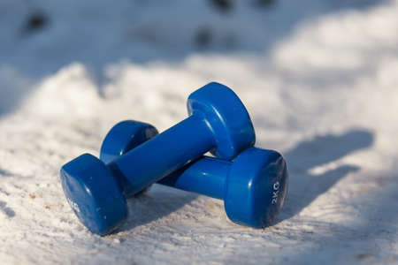 Two dumbbells lie on the snow. Equipment for sports in the open air in winterの写真素材