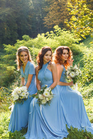 Three beautiful bridesmaids in the park on wedding dayの写真素材