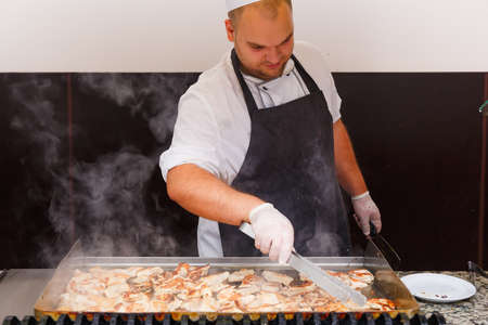 NESSEBAR, BULGARIA - AUG 26: Man take cooking of chicken meat on restaurant kitchen in hotel Marvel, Nessebar, Bulgaria at August 26, 2016のeditorial素材