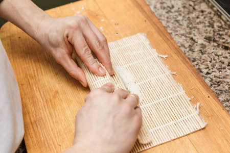 Preparing, rolling sushi. Close up of the hands of sushi master.の写真素材