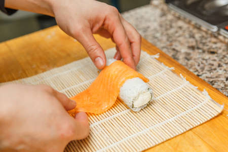 Preparing, rolling sushi. Close up of the hands of sushi master.の写真素材