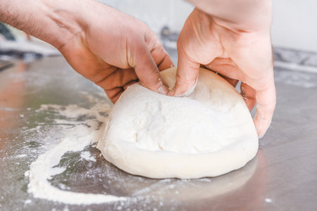 Cook forms a dough pizza base. Hands closeup.