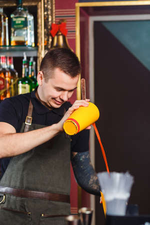 The bartender making cocktail in a nightclub bar. Pouring tomato juice.の写真素材