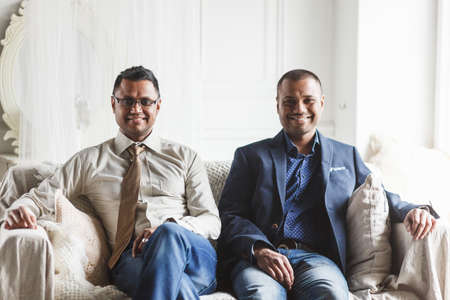 Image of two young African men sitting in room and looking at cameraの写真素材