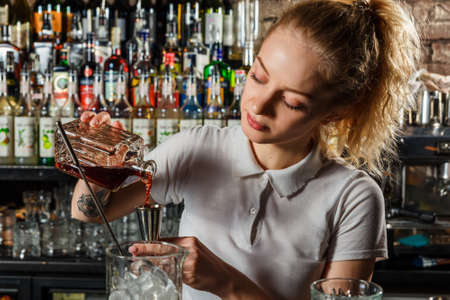 Woman bartender making an alcohol cocktail at the barの写真素材