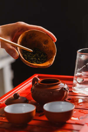 The process of brewing tea at the tea ceremony. The woman poured the dry tea in the teapot.の写真素材