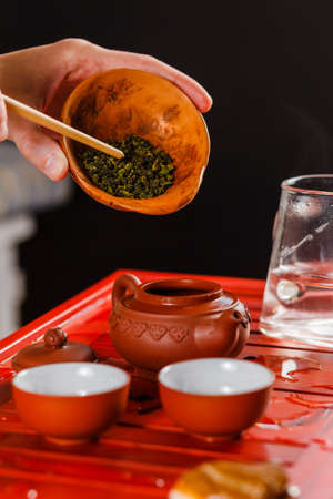 The process of brewing tea at the tea ceremony. The woman poured the dry tea in the teapot.の写真素材