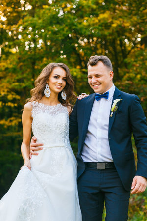 Elegant curly bride and stylish groom walking in beautiful summer parkの写真素材