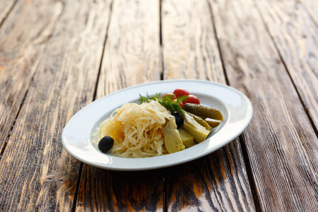 Pickled vegetables. Appetizer of tomatoes, cucumbers, cabbage and pepper close-up in white plate on the wooden tableの写真素材
