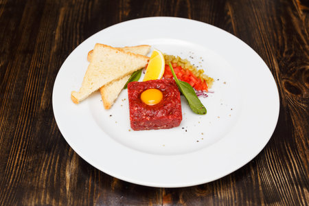 Delicious classic steak tartar with beef, pepper, onion and slices of bread, close-upの写真素材