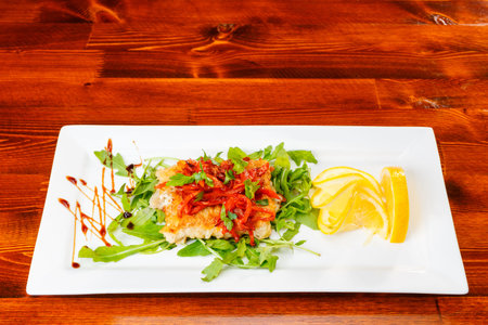 Roasted fish with stew carrots and onion decorated with arugula
