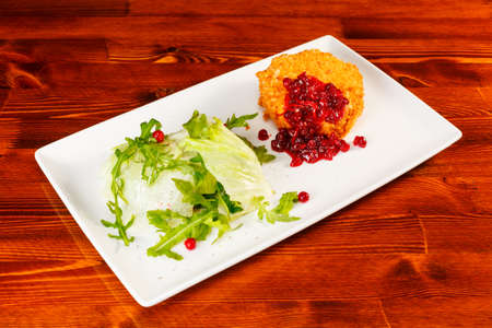 Baked camembert with cranberry sauce and romaine lettuce on big white plateの写真素材