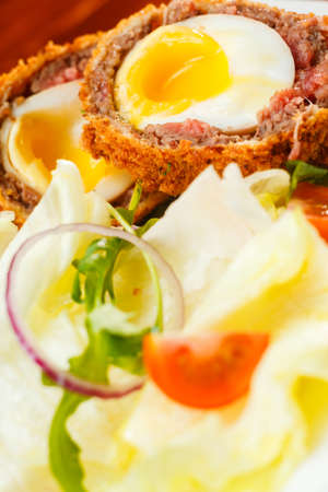 English food, Scotch eggs served with lettuce, toatoes and sauceの写真素材