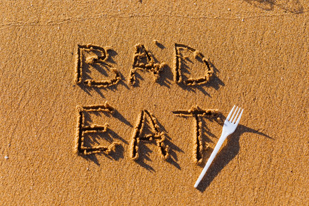 Text Bad Eat written on sand beach