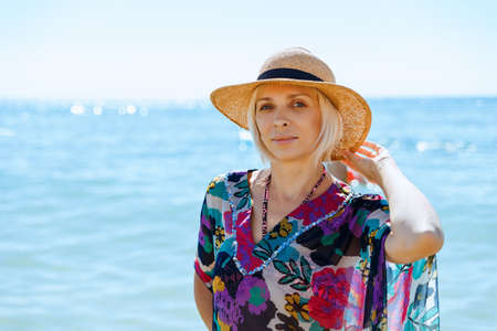 Young woman in dress and straw hat posing on seaの写真素材