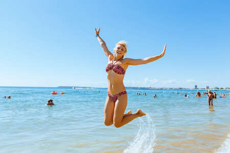 Young happy woman in bikini jumping in the seaの写真素材