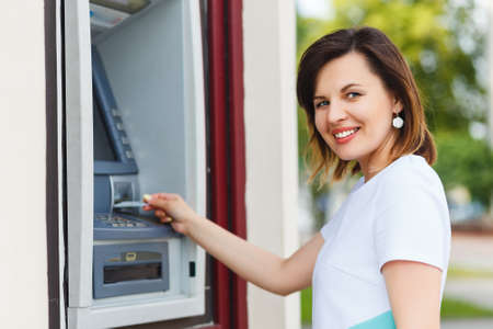 Young beautiful woman using an ATM to get cashの写真素材