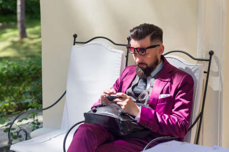 A young handsome businessman sitting and using smartphoneの写真素材