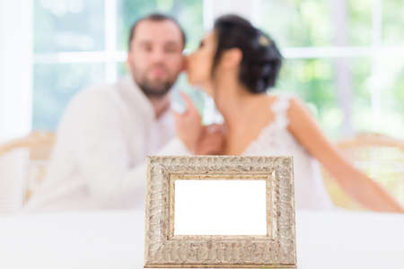 Empty frame on the background of the kissing bride and groom.の写真素材
