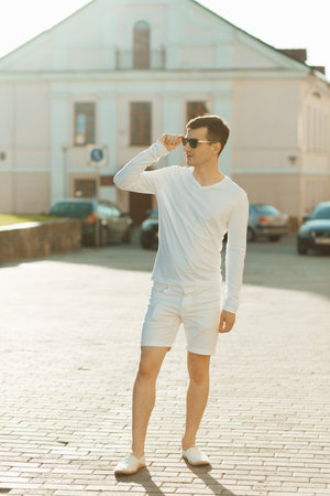Young handsome man in white wear posing on a streetの写真素材