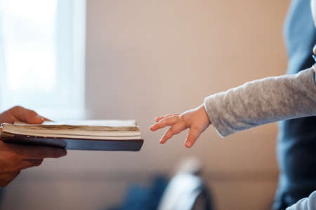 A little child pulls his hand to the Bible during the rite of baptismの写真素材