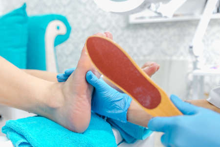 Pedicure master during work. Closeup of female feet and hands in gloves with a nail file.の写真素材