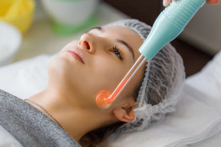 Violet ray treatment on face at the beautician. A violet ray is an antique medical appliance used during the early 20th century in the obsolete medical therapy called electrotherapy.の写真素材