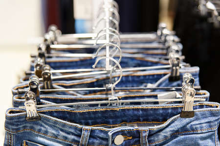 Set of blue jeans hanging on hangers in shopの写真素材