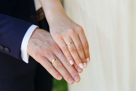 Bride and groom holding hands with wedding ringsの写真素材