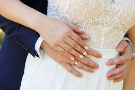 Bride and groom holding hands with wedding ringsの写真素材