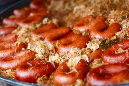 Process of cooking european traditional food. Big plate of stewed sausages with cabbage. Chef cooking on the street during the holiday of the city Druskininkai, Lithuania.の写真素材