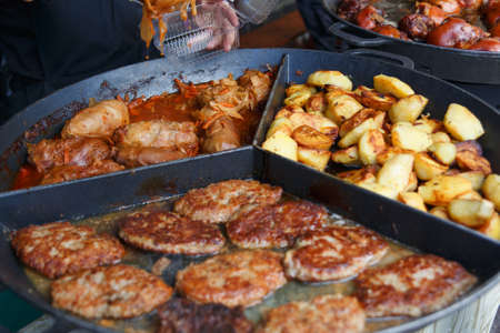 Process of cooking european traditional food. Big plate of fried potato pancakes and stuffed cabbage. Chef cooking on the street during the holiday of the city Druskininkai, Lithuania.の写真素材