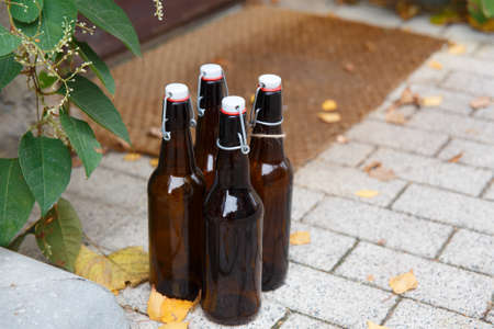 Four empty beer bottles are waiting on the porch of the houseの写真素材