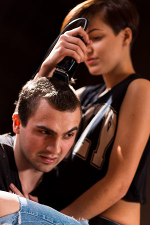 Young punk girl cuts her boyfriend using clippers.の写真素材