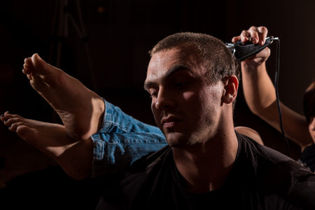 Young punk girl cuts her boyfriend using clippers.の写真素材