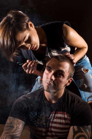 Young punk girl cuts her boyfriend using clippers.の写真素材