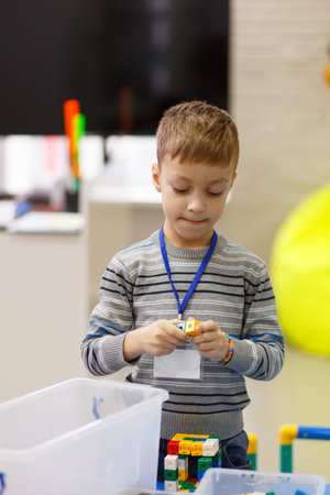 Little boy playing with blocks in the school of digital technology.