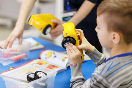 The boy collects a model of a radio-controlled car from the blocks of an electronic-mechanical...