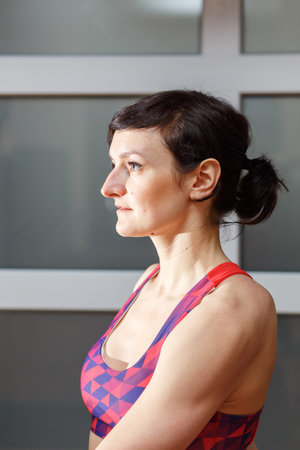 Young sporty woman practicing yoga, doing Sukhasana exercise, Easy Seat pose, working out, wearing...