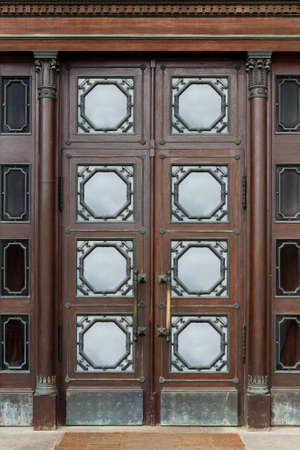 Old massive swinging wooden glazed doors with metal ornaments in the historic buildingの写真素材