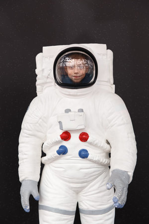 Portrait of a cute young boy in a space suit against the starry sky.