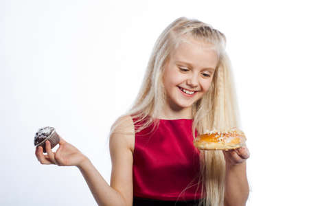 Girl making a choice between two cakes. Isolated on white background.の写真素材