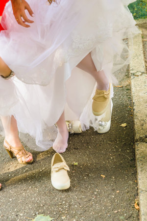 Bride change shoes sneakers on wedding walk in parkの写真素材