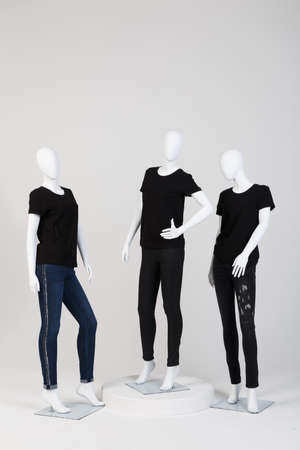 Three female mannequins dressed in fashionable black clothes over white  background.の写真素材